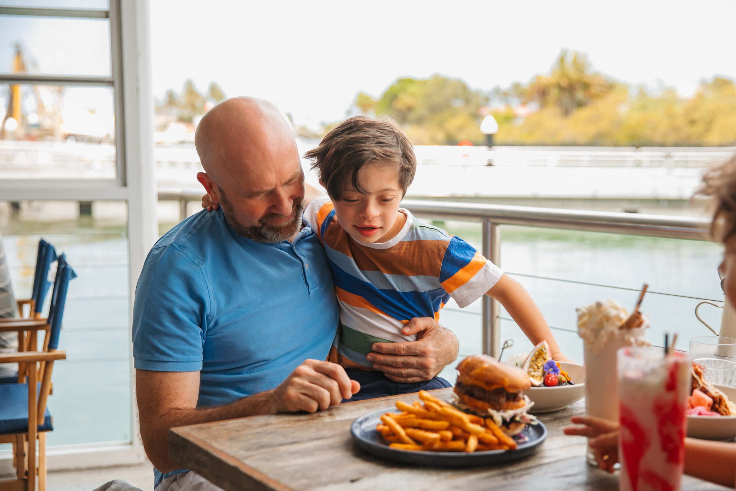 Family enjoying an inclusive travel holiday, having lunch by the water at Baked at Ancora in Tweed Heads